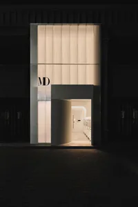 Modern retail storefront featuring framed glass panels at night.