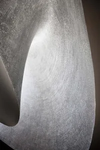 A close-up image of a textured, abstract metal sculpture created from mosaic tiles.