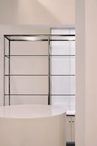A minimalist interior design featuring glass shelves against a white wall.