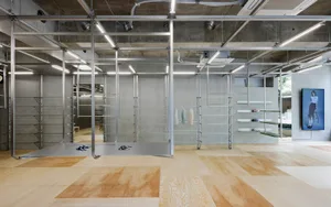 Modern minimalist shop interior with steel shelves, concrete walls, and wooden flooring.