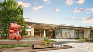 Concrete, glass, and metal modern entrance with a large, abstract mural and fountains.