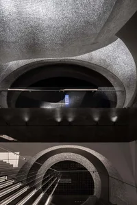 Luxurious modern interior with glass mosaic floor, stone archways, and metallic railings.