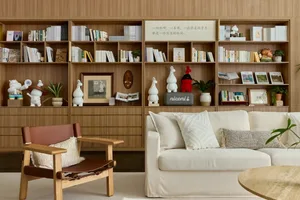 A modern living room with white furniture and wooden shelves filled with books and decorative items.