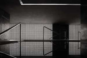 Modern minimalist interior with steel and concrete elements, featuring perforated glass and geometric design.