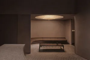 Modern living room with concrete tiles, circular light fixture, and circular couch.