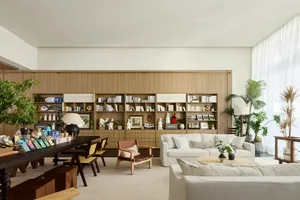 A modern living room with wooden shelves displaying books and collectibles, and white sofas.