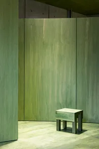 An empty room with minimalist design, featuring concrete walls, floors, and furniture.