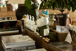 A well-organized bookstore display featuring ceramic planters, books, and decorative animals on a wooden counter.