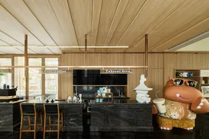A modern bar with a wooden and marble interior, featuring stools, stools, and a large hippo figure.