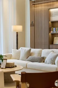 A modern living room with a white sofa, wooden coffee table, and glass lamp.