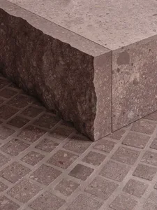Concrete bench with a rough texture placed on a patterned concrete floor.
