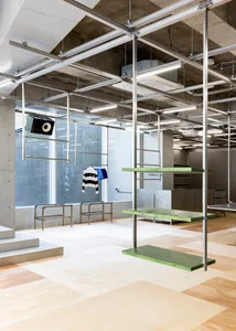 Modern interior design of a clothing retail shop with green and metallic shelves.