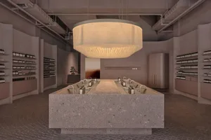 Modern retail shop with concrete and terrazzo furniture, featuring a central island with multiple sinks and bottles of produc