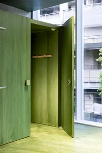 An open green wooden door in an industrial-style interior space, featuring green flooring and walls.
