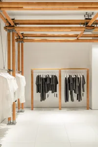 Modern clothing store interior with white walls, bamboo accents, and clothing racks.