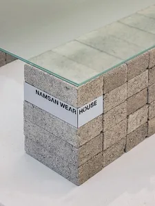 A minimalist desk with a glass top and a base made of stacked concrete blocks.