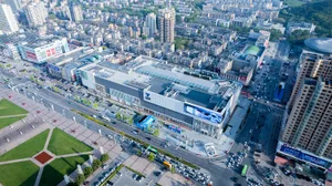 A spacious commercial district featuring a modern shopping center with concrete and glass architecture, surrounded by numerou