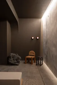 A minimalist living space featuring concrete walls and wood furniture.