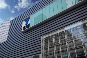 A modern shopping mall exterior featuring metal cladding and glass panels on a sunny day.