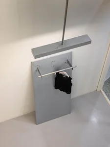 Metal clothing rack with a black knitted vest hanging.