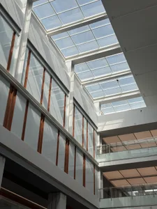 A modern office space featuring glass walls and concrete structural elements.