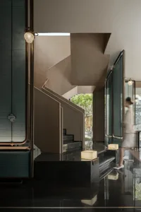 Modern residential staircase with a black marble floor and metallic railings.