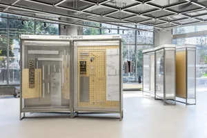 An exhibition display featuring metal and wood prop-building elements in a modern, industrial setting.
