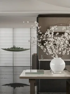 A minimalist interior design featuring a large vase with white flowers on a table.