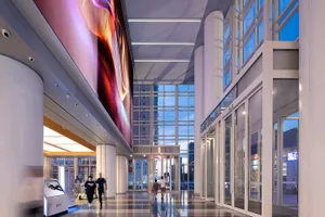 A spacious, modern commercial space featuring glass columns and a large, illuminated wall.
