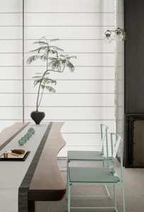 A modern dining room featuring a live-edge wooden table, glass vase with plant, and glass and metal chairs.