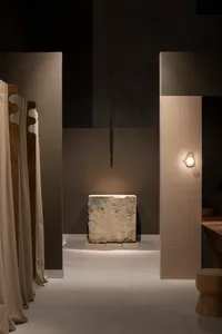 A modern bathroom interior featuring a large stone block on a pedestal, illuminated by subtle lighting and surrounded by mini
