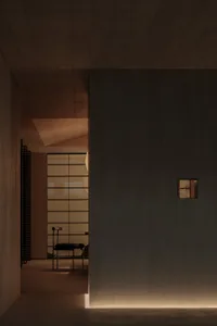 A minimalist concrete interior space with a single chair and a small window.
