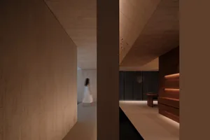 A minimalist interior space with concrete walls and floors, featuring subtle lighting and a sleek wooden cabinet.