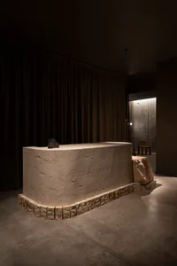 A modern concrete reception desk in a dimly lit interior space.