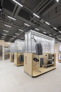 Modern retail interior featuring a suit-fitting booth with a wooden structure and acrylic panels.