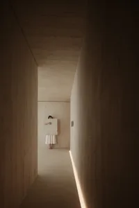 Person standing in a minimalist concrete hallway.