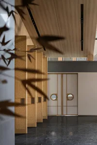 Hotel entrance with wooden framed doorway featuring round glass panels and minimalist design