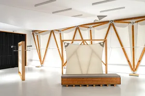 A minimalist interior design featuring wooden frames and light-colored textiles.