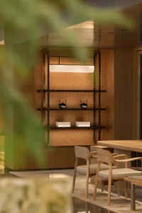 A modern dining room featuring wood shelves with kettles and boxes.