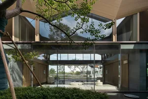 Modern residential interior featuring large glass walls and a prominent brick feature