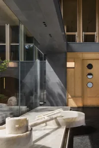 A modern interior space featuring a marble fountain, with a mix of glass and wooden elements, and a sleek, contemporary desig