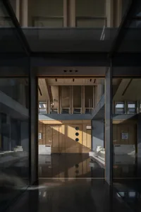 A modern lobby with wooden panels and glass walls, featuring sleek design elements.