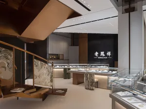 Modern retail store with concrete and glass walls and metal accents, featuring jewelry displays and a staircase.