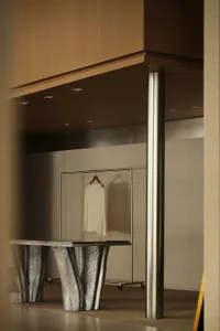 Metallic table in a retail space with a white garment on a hanger.