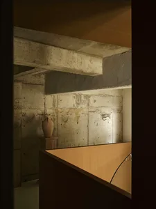 A minimalist interior design featuring concrete walls and a wooden floor.
