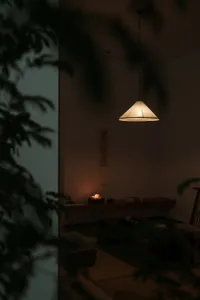 A minimalist cozy lounge area with a paper lampshade, candles, and a traditional Japanese writing scroll hanging on the wall.