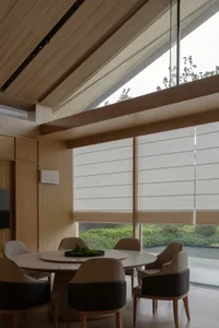 A minimalistic dining room featuring upholstered chairs and fabric blinds.