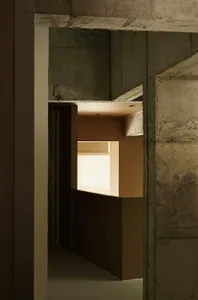 A minimalist interior space with concrete walls and ceiling, featuring a bright light source.