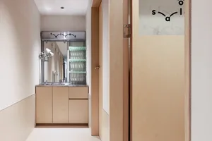 A modern bathroom with wood cabinets, minimalistic design, and glass shelves.