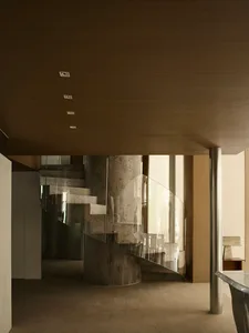 Modern industrial staircase with concrete steps, glass railing, and steel columns.